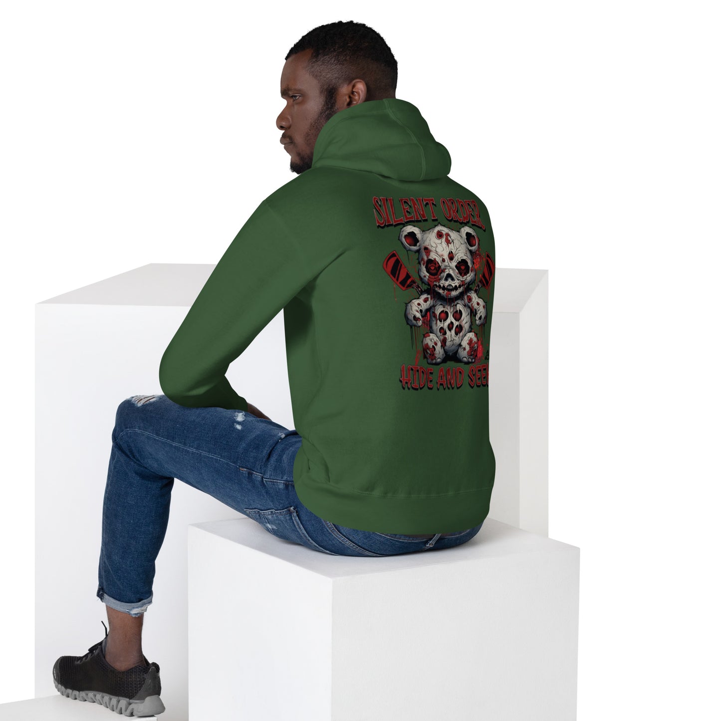 Person wearing a green hoodie with a graphic design on the back, sitting on a white cube.