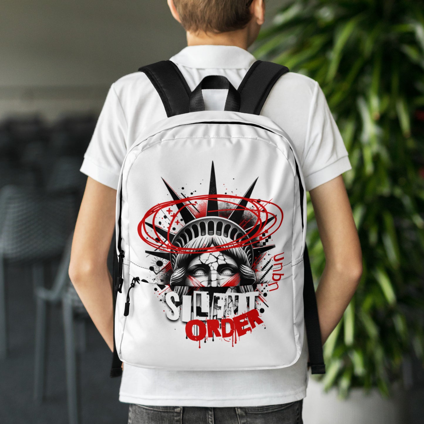 Person wearing a white backpack with a graphic design and text, standing outdoors.