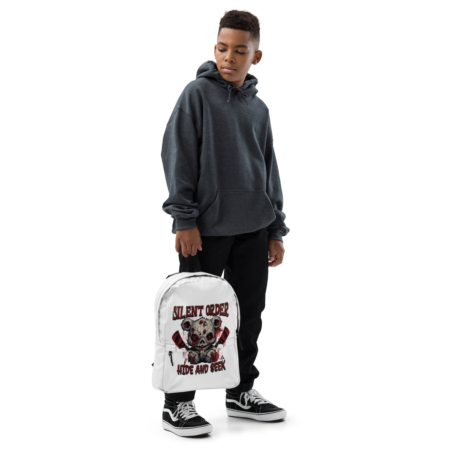 Child wearing a gray hoodie and black pants, holding a white backpack with a graphic design on a white background