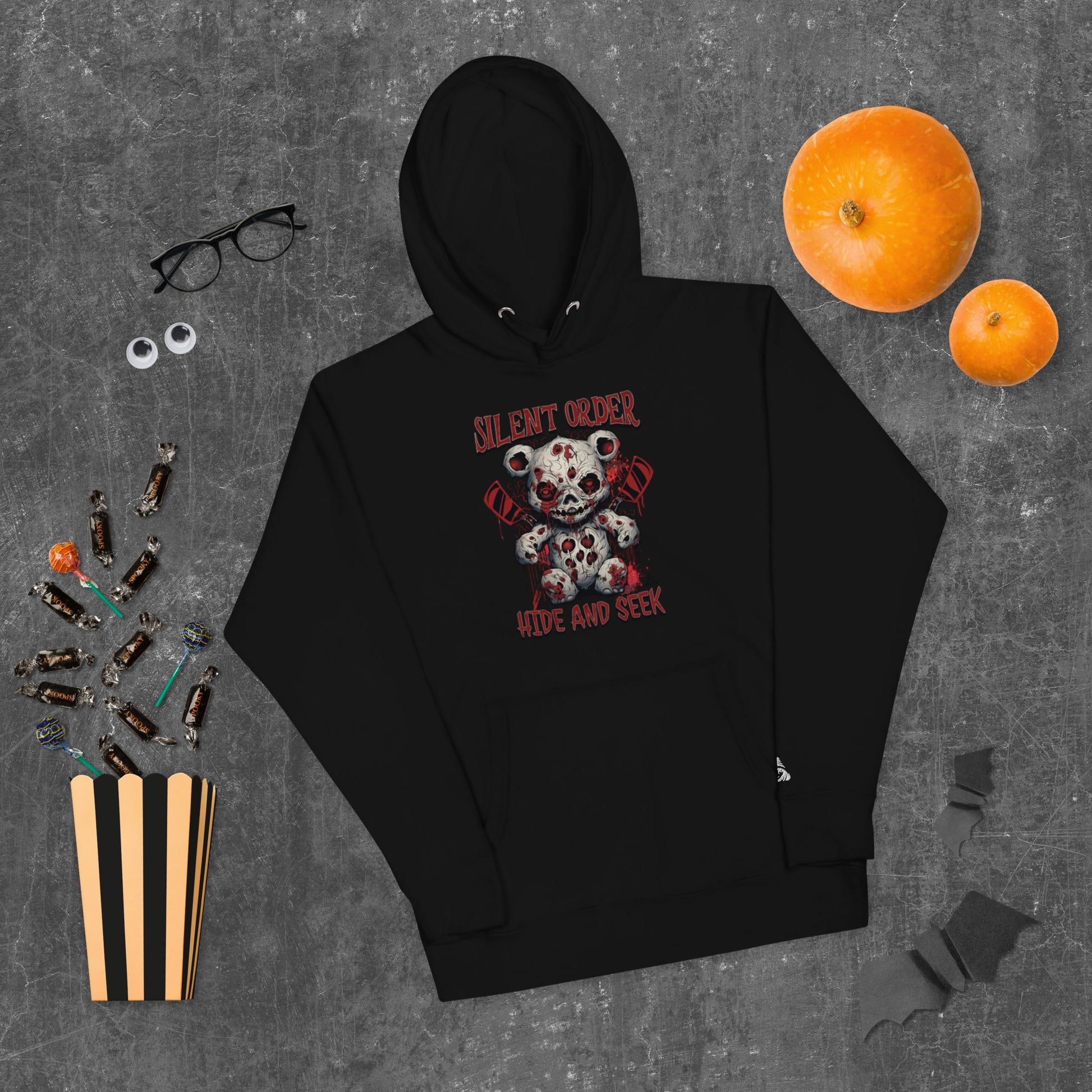 Black hoodie with a graphic design on a gray surface with Halloween items.