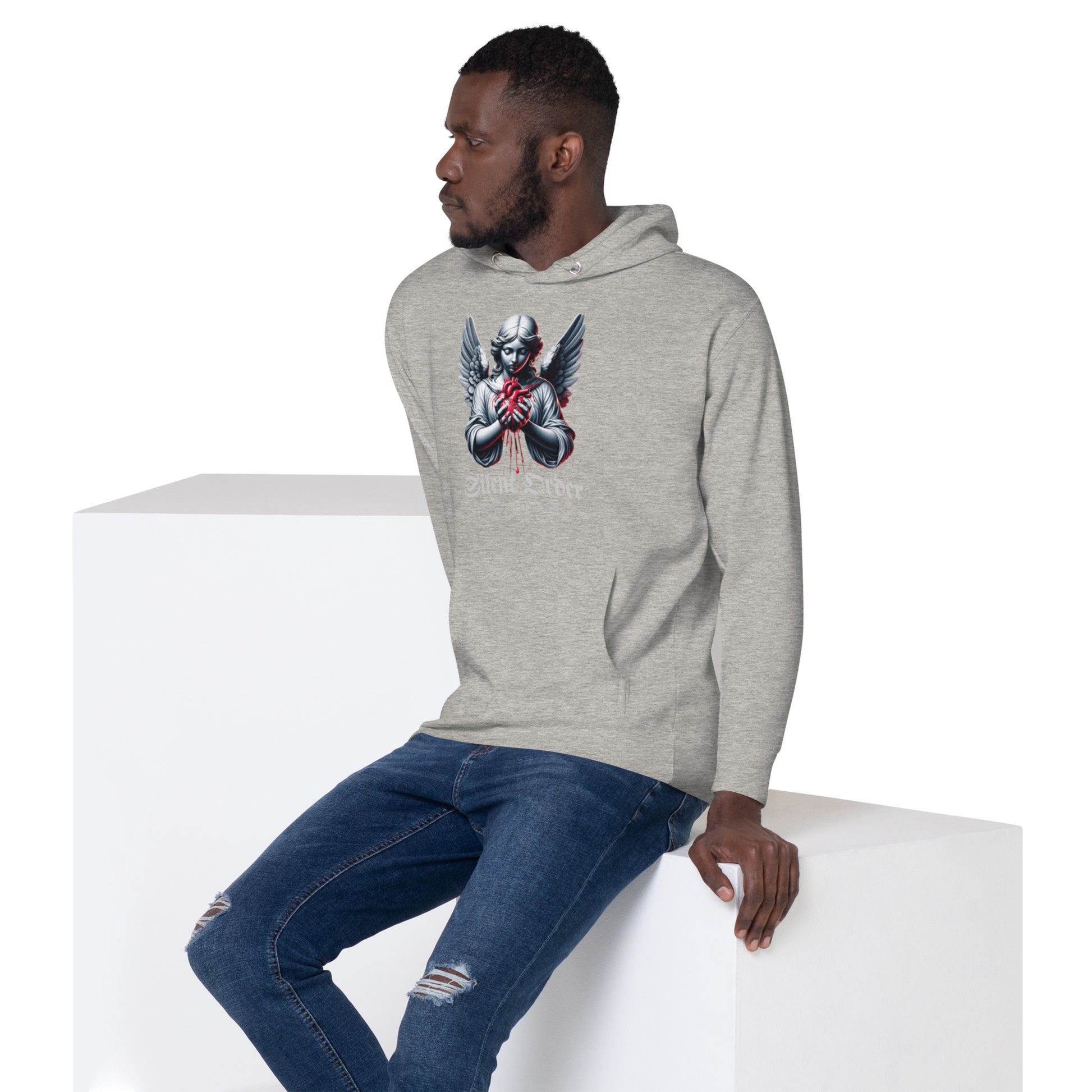 Man wearing a gray hoodie with a graphic design sitting on a white cube.